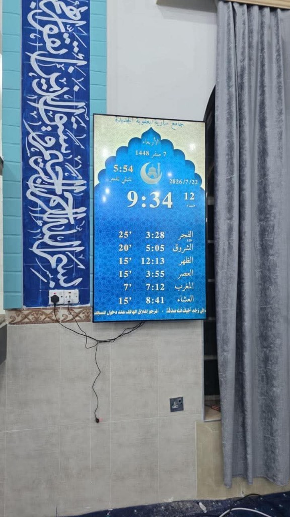 شاشة عمودية بجانب لوحة قرآنية
